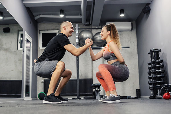 Couples Personal Training Holding Hands and Squatting